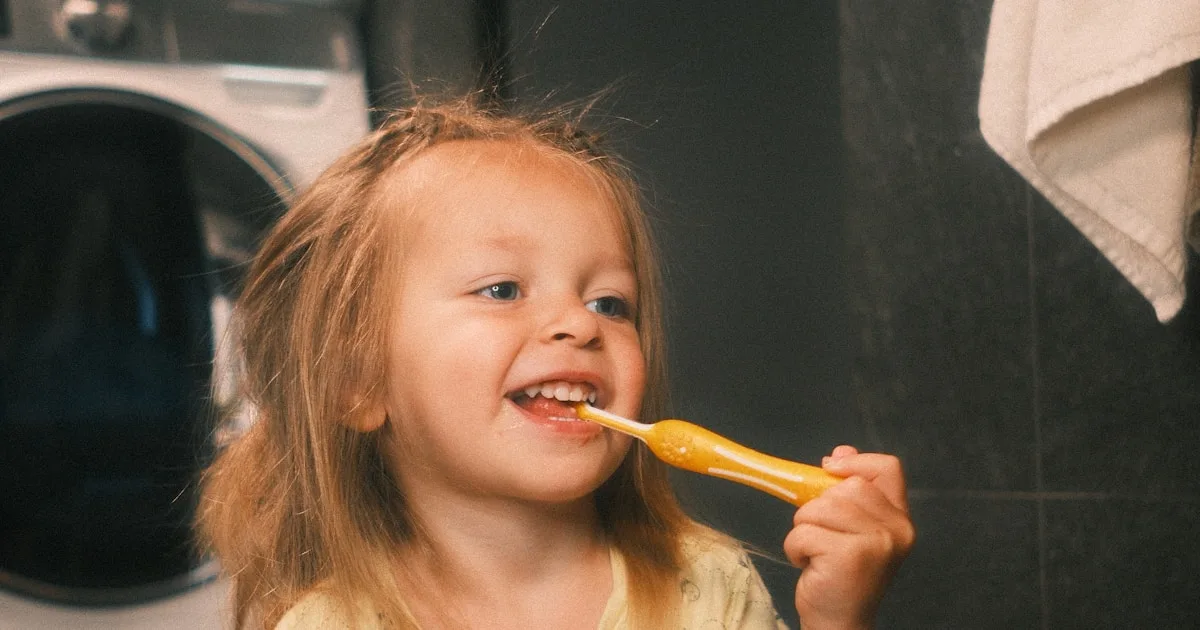 Smiling young child brushing her teeth with a fluoride toothpaste — cavity prevention for families in Royal Palm Beach, FL