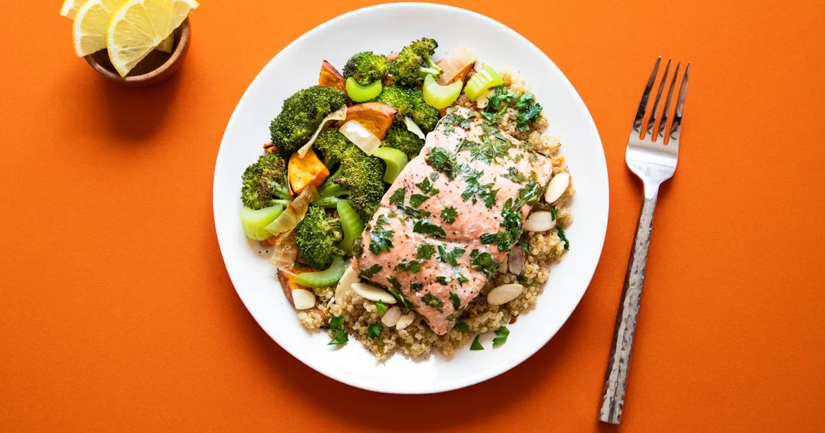 Baked salmon with broccoli, quinoa and almonds on a white plate — omega-3 rich foods that support gum health, Family Dentist of Palm Beach, Royal Palm Beach, FL